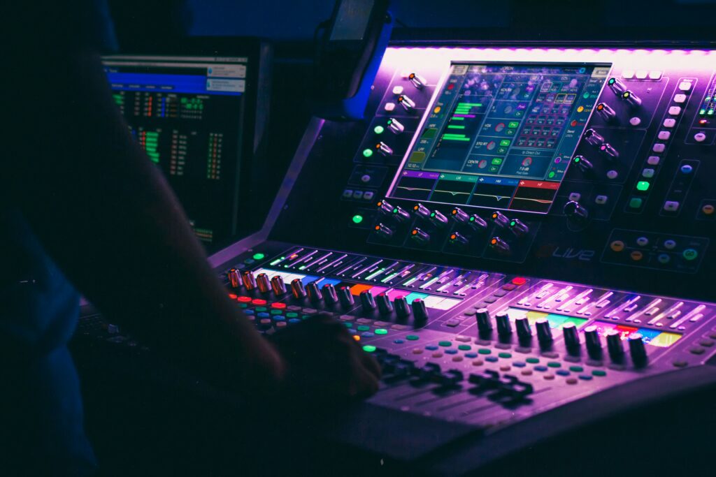 Une personne face à une table de mixage, manipulant les faders et boutons pour créer un son équilibré