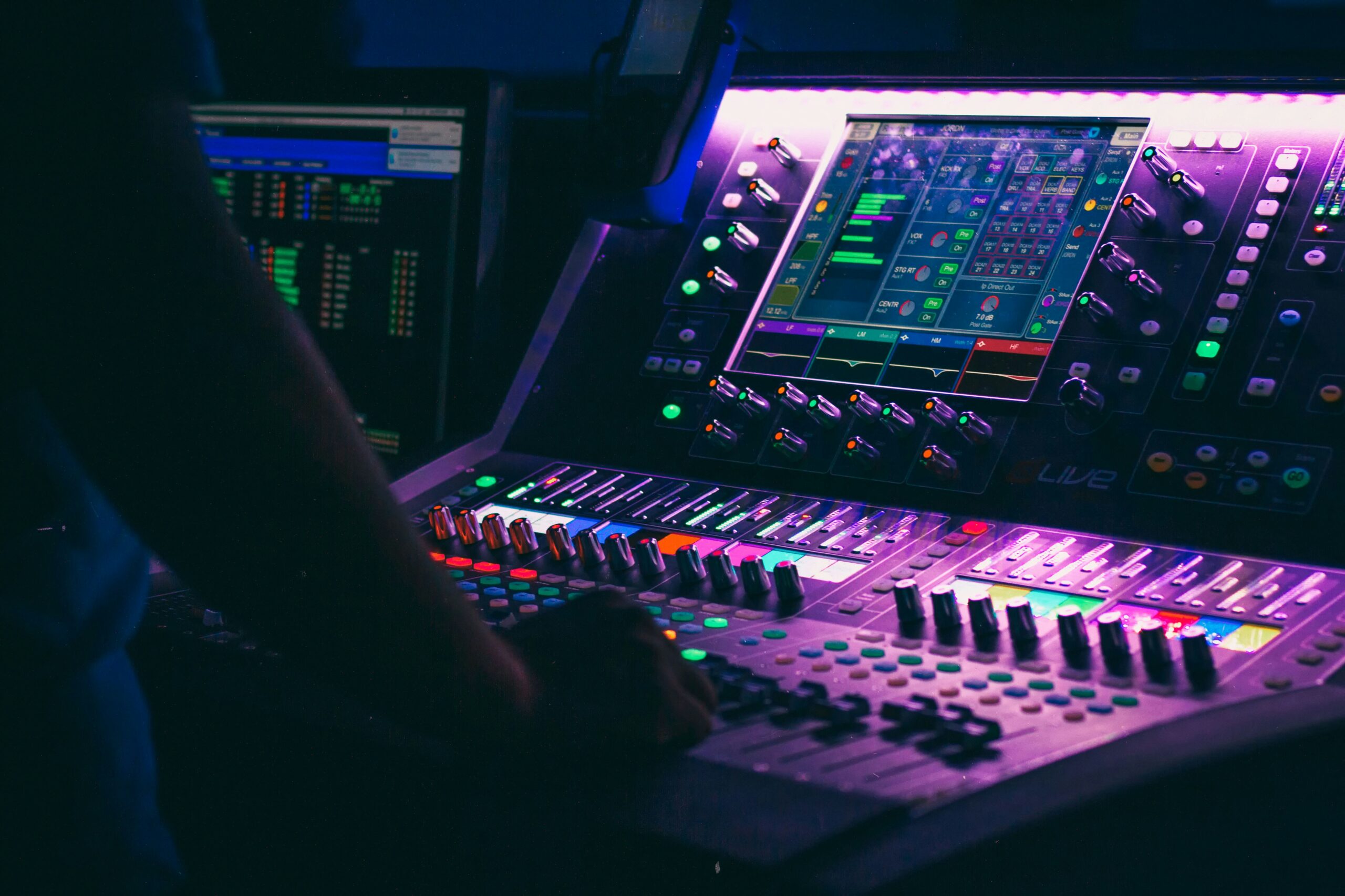 Une personne face à une table de mixage, manipulant les faders et boutons pour créer un son équilibré